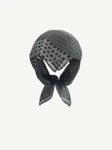 Close-up view of a stylish black and white polka dot and striped patterned square scarf detail.