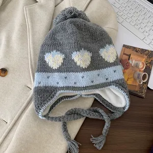 Detailed view of the cute grey knit earflap hat featuring sweet strawberry jacquard and pom-pom.