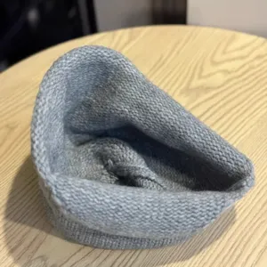 Close-up view of a soft grey knitted fisherman hat showing fine texture and rolled edge design.
