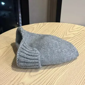 Gray knitted fisherman hat detail shot, showing soft wool texture and rolled brim style.