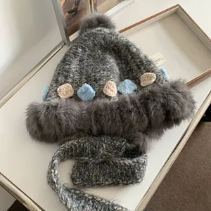 Grey wool knit trapper hat detail showing plush ear flaps and cute crochet flower patches.