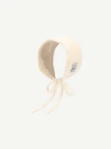 Gros plan détaillé du bonnet en tricot doux, mettant en valeur le tissu et l'étiquette latérale.