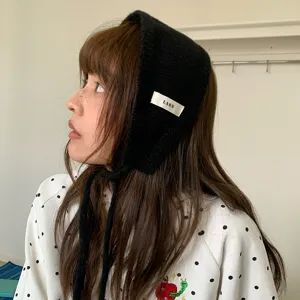 Gedetailleerd shot van minimalistische zwarte gebreide oorwarmer met stoffen label.