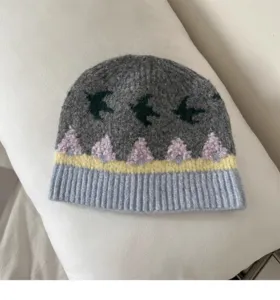 Nahaufnahme einer retro jacquardgestrickten Wintermütze mit Vogel- und Baummustern.