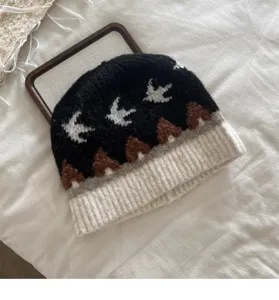 Detailansicht einer Retro Strickmütze mit Vogel und Baummuster sowie Rippbündchen.