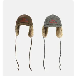Retro tweed trapper hat with cozy faux fur earflaps and long strings for winter warmth.