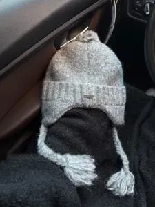 Grey knitted earflap beanie hat with braided tassels and pom pom, winter warm windproof cap.