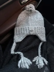 Stylish grey knitted trapper hat with fluffy pom pom earflaps, warm cozy winter windproof cap.