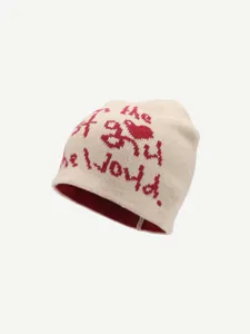 Detailed view of the cozy knitted beanie in beige with red jacquard lettering and lining.