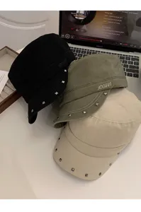 Toma detallada de gorras militares retro con tachuelas, sombreros planos multicolores.