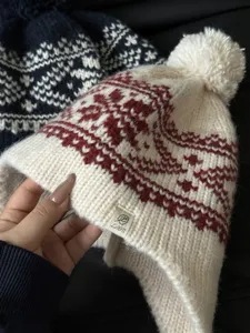 Detailed view of retro jacquard knitted earflap beanie hat with fluffy pom-pom for winter warmth.