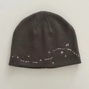 Close-up detail of dark grey knit beanie with cute pink embroidered stars and letters.