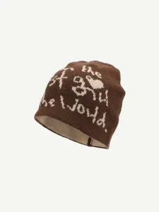 Close-up detail of the brown knit beanie showcasing unique jacquard lettering texture.