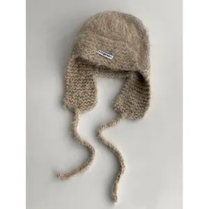 Fluffy mohair knitted earflap trapper hat with braided ties, cozy winter warm hat detail view.