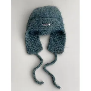Fluffy mohair knitted trapper hat with earflaps and braided ties for winter cozy warmth.
