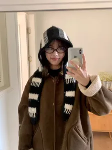Dettaglio sciarpa con cappuccio a righe bianco e nero, cappello caldo invernale.