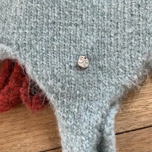 Close-up detail of winter warm knitted wool hat, soft light blue texture with metal bow.