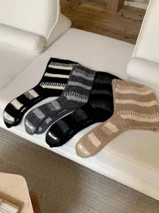 Primo piano dettagliato di comodi cappucci e sciarpe in maglia a righe, morbida consistenza.
