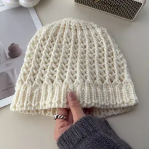 Detailed shot of a beige hollow knit beanie hat, soft wool-blend retro winter warm cap.