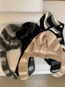 Dettaglio berretto lavorato a maglia con orecchie di coniglio, filato morbido e righe.