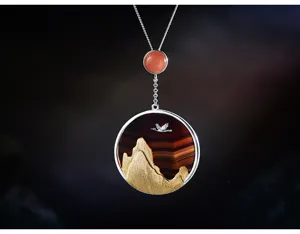 Détail de pendentif montagne et grue en argent exquis, design élégant pour bijoux de femme.