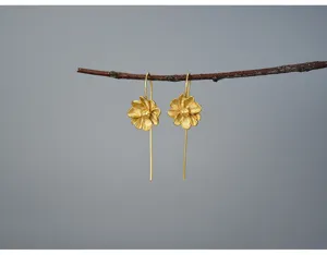 Close-up of matte gold jasmine flower drop earrings hanging on a branch, fine sterling silver.
