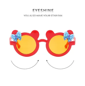 Cute kids cartoon bowknot sunglasses with round yellow lenses and red frames for summer beach.