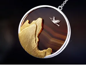 Détail raffiné du pendentif en argent sterling avec relief de montagne dorée et grue sur agate.