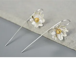 Detailed view of sterling silver flower hook earrings with gold centers, elegant design.