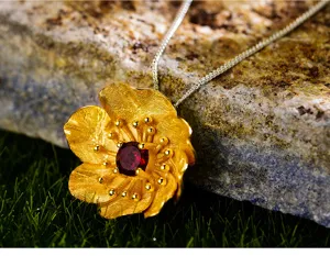 Ciondolo fiore in argento S925 e granato naturale primo piano, gioiello artigianale di lusso.