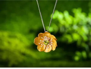 Primo piano dettagliato di un ciondolo a fiore in argento sterling placcato oro con gemma verde.