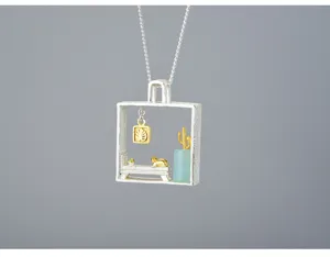 Dettaglio del ciondolo gatto in argento con raffinato paesaggio in miniatura e pietra preziosa.