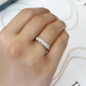 Nahaufnahme Detailansicht eines funkelnden Fünf-Stein-Moissanit-Bandrings an einer asiatischen Hand.