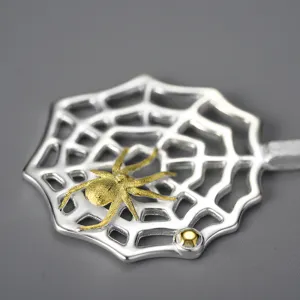 Detalle de primer plano del colgante de telaraña de plata con una bonita araña dorada.
