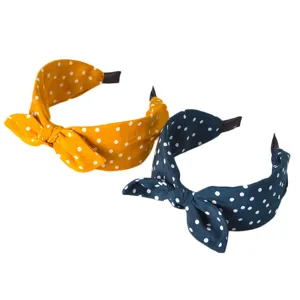 Vista dettagliata di eleganti cerchietti per capelli in tessuto a pois gialli e scuri.