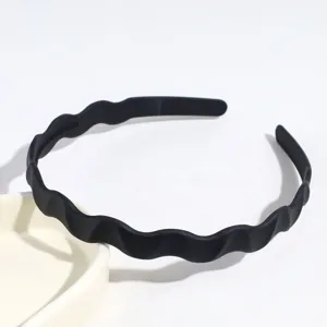 Serre-tête ondulé noir en plastique, accessoire capillaire minimaliste pour le visage et style.