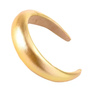 Détail en gros plan du serre-tête rembourré en cuir métallisé doré, large et chic.