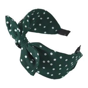 Dettaglio di cerchietto a pois verde scuro, elegante accessorio per capelli fiocco.