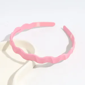 Gros plan détaillé du serre-tête en plastique rose ondulé, affichant un design à vagues.