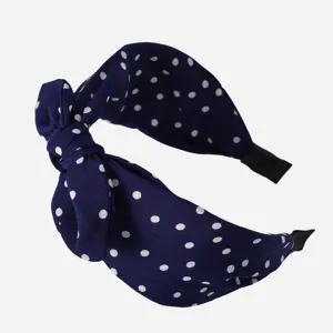 Primo piano dettaglio della fascia per capelli in tessuto a pois blu scuro morbido.