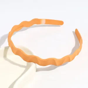 Détail en gros plan d'un cerceau à cheveux ondulé orange minimaliste pour un usage quotidien.