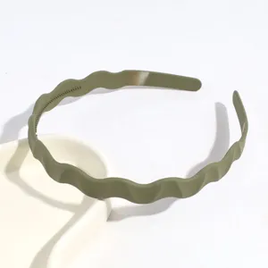 Vue détaillée d'un serre-tête ondulé vert en plastique, idéal pour le lavage quotidien et loisirs.