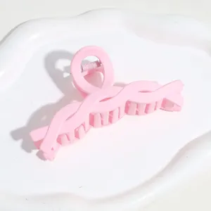Détail de pince à cheveux torsadée rose, gros plan de pince requin mate pour coiffure.