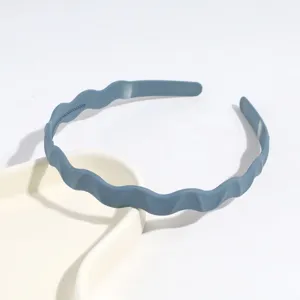 Vue détaillée d'un serre-tête en plastique ondulé bleu, accessoire minimaliste élégant.