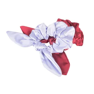 Satin hair scrunchie detail shot, elegant purple rabbit ear bow and red elastic hair tie.
