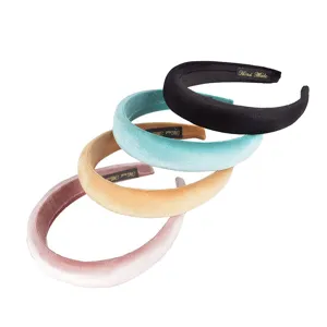 Detailed shot of thick velvet padded headbands in various chic colors with handmade labels.