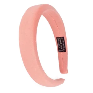 Detailed view of the solid pink padded fabric headband showcasing its inner handmade label.