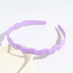 Vue détaillée d'un serre-tête ondulé violet en plastique, accessoire élégant pour un usage quotidien.