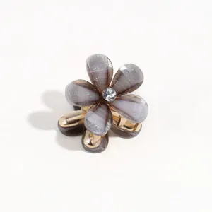Mini flower hair claw detail shot, grey glitter petals, gold metal base and rhinestone accent.