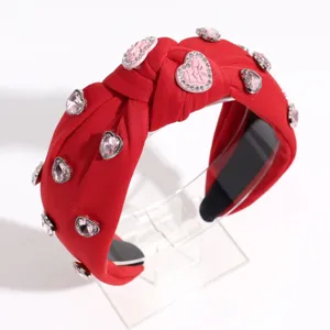Gros plan sur le bandeau noué rouge, orné de strass cœurs rose étincelants et élégants.